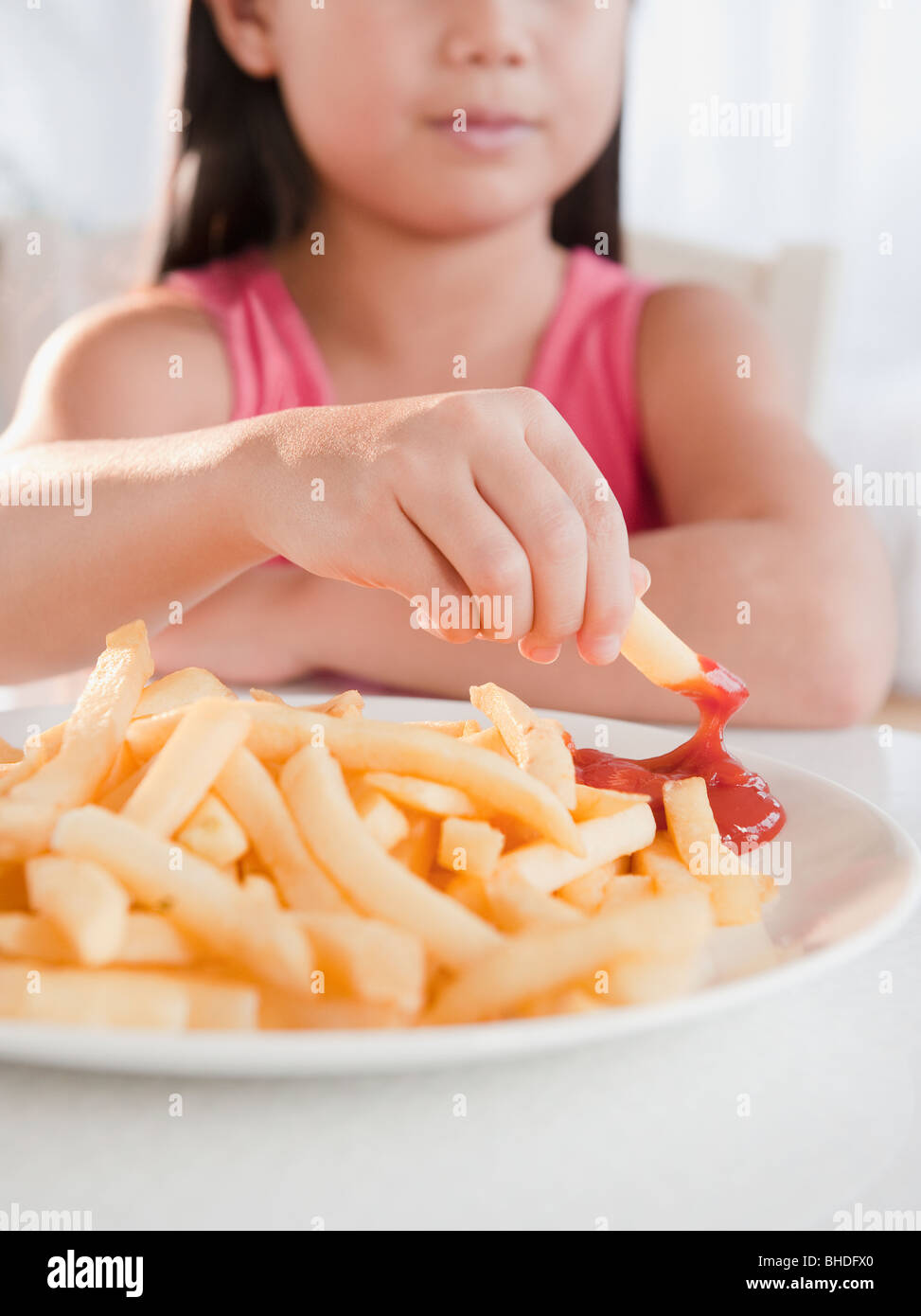 Mixed Race girl eating French Fries et ketchup Banque D'Images