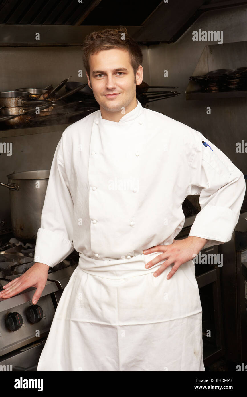 Male Chef debout à côté d'une cuisinière dans une cuisine de restaurant Banque D'Images