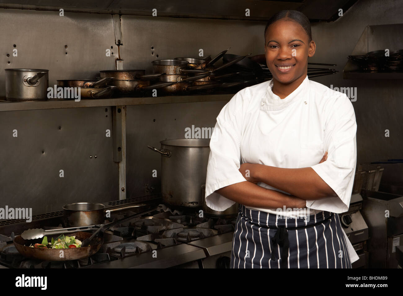 Femme Chef debout à côté d'une cuisinière dans une cuisine de restaurant Banque D'Images