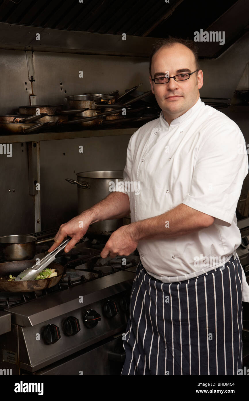 Male Chef Preparing Meal sur cuisinière dans une cuisine de restaurant Banque D'Images