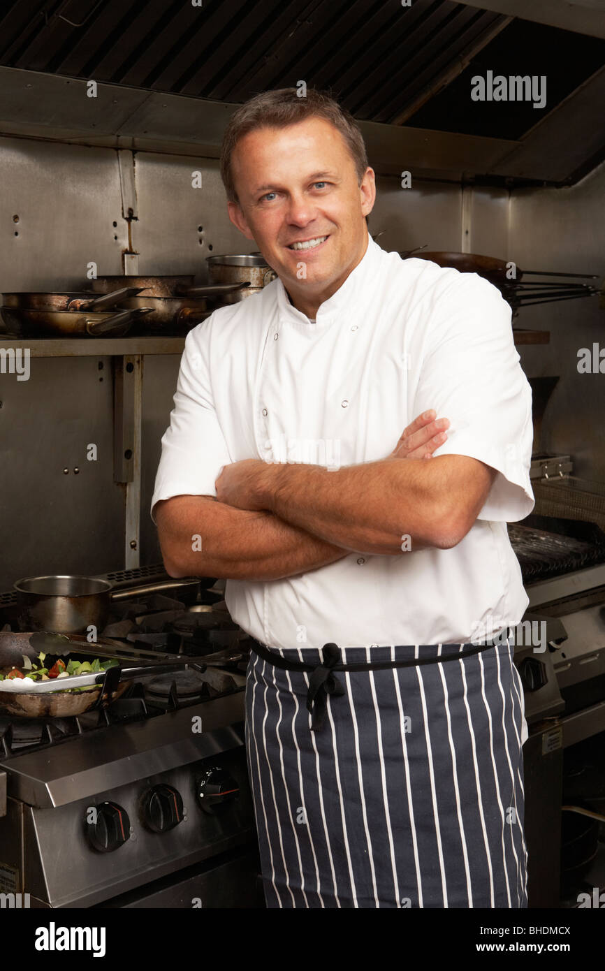 Male Chef debout à côté d'une cuisinière dans une cuisine de restaurant Banque D'Images