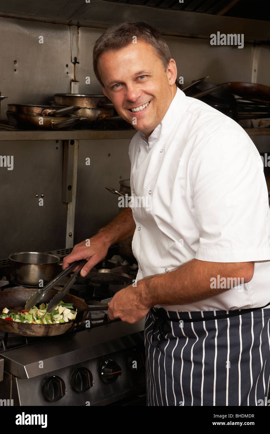 Male Chef Preparing Meal sur cuisinière dans une cuisine de restaurant Banque D'Images