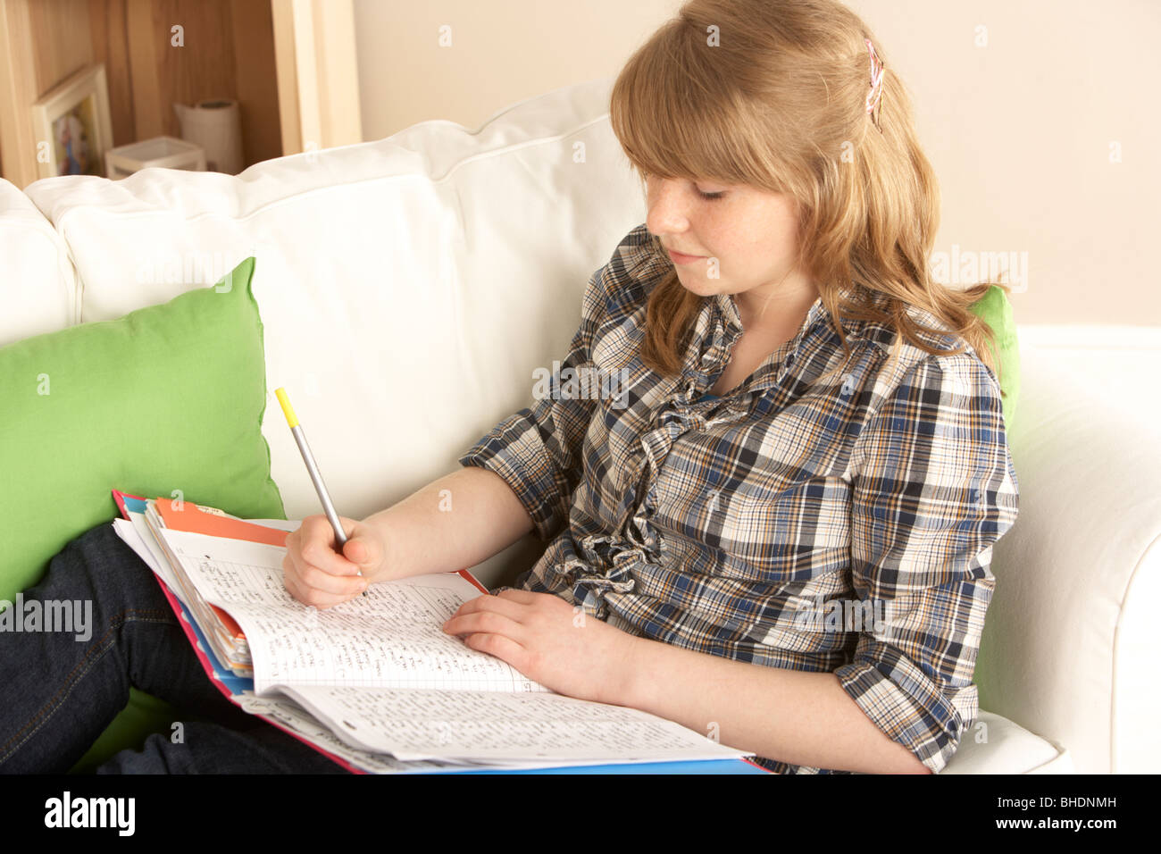 Teenage Girl studying at home sitting on Sofa Banque D'Images