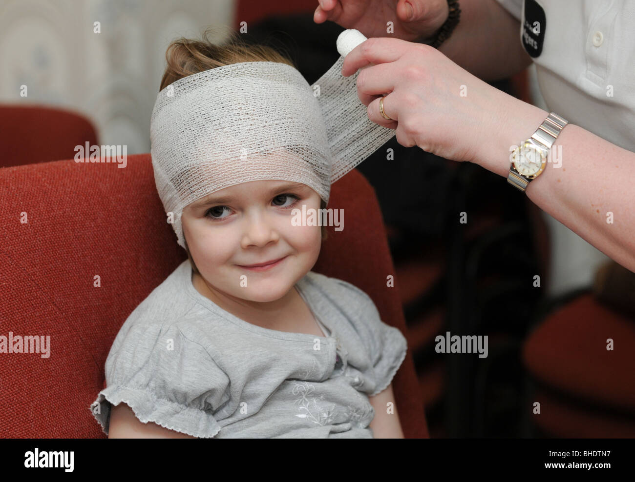 Les premiers soins effectués sur une petite fille qui a nui à sa tête dans un accident de jeu et sa tête est bandée Banque D'Images