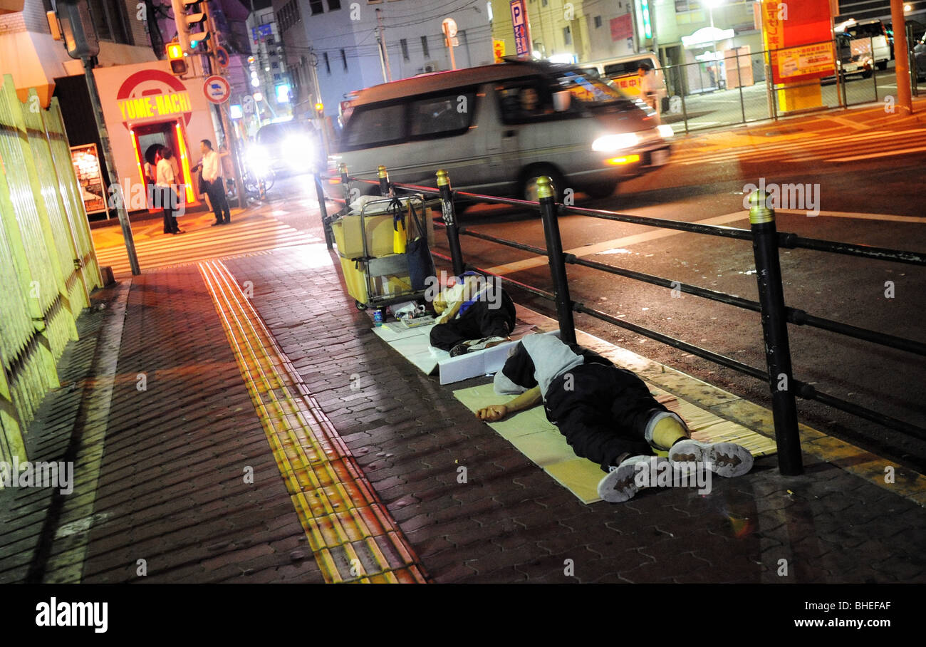 Les chômeurs et les hommes sans-abri dormir sur le bord de la route dans le centre de Osaka, Japon. Banque D'Images