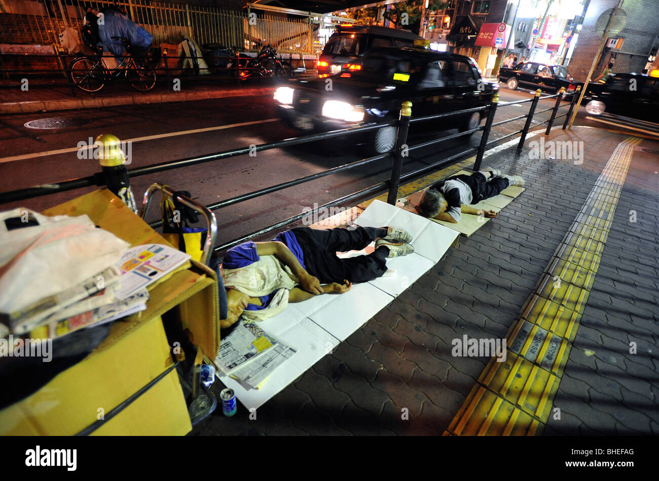 Les chômeurs et les hommes sans-abri dormir sur le bord de la route dans le centre de Osaka, Japon. Banque D'Images