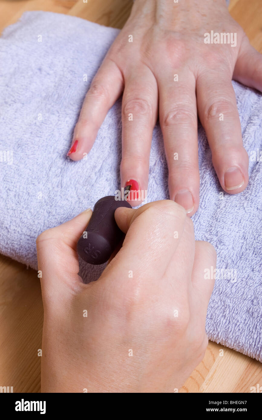 74 ans femme avec mains arthritiques recevant des soins de spa / manucure. Banque D'Images