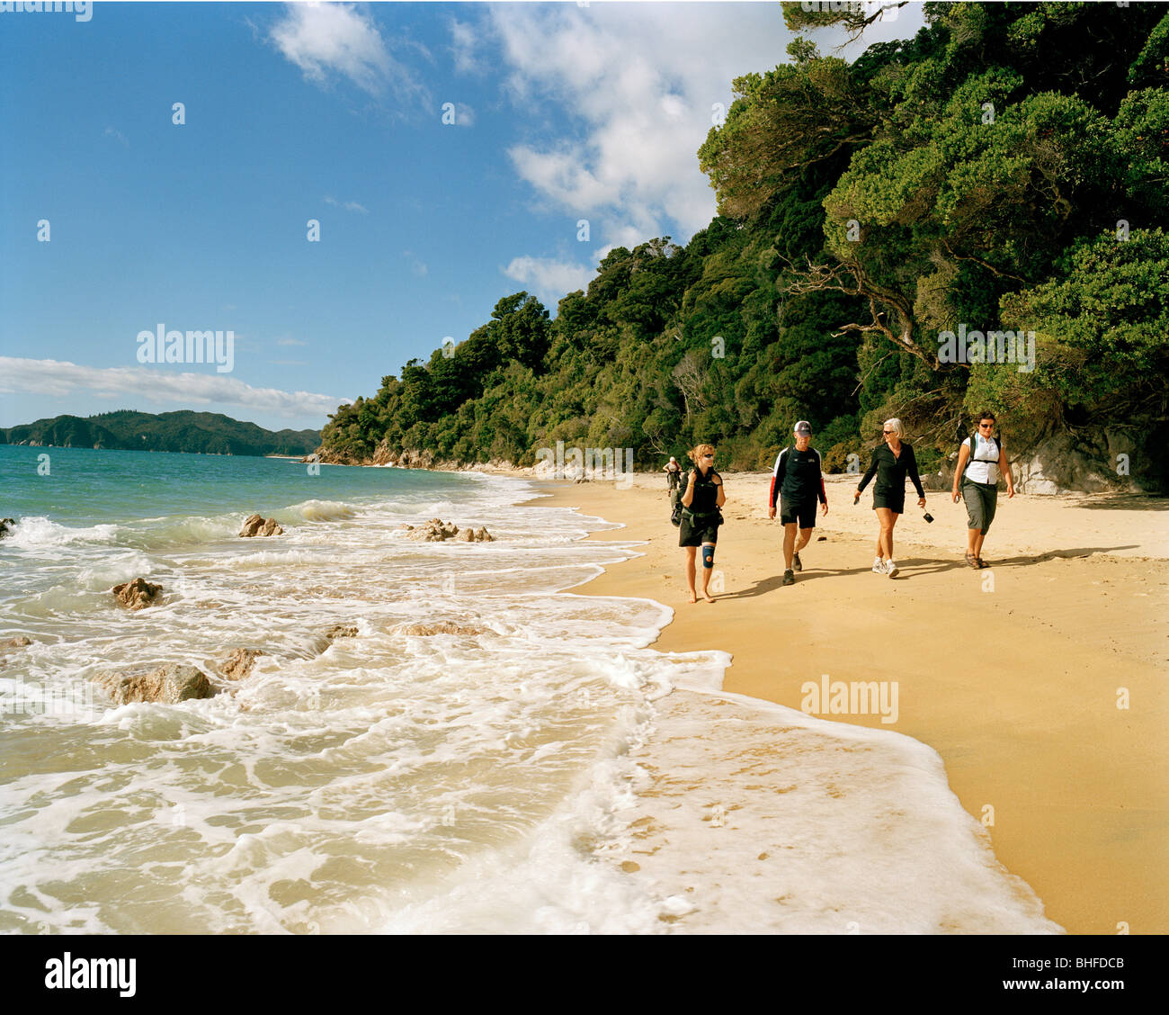 Randonneurs sur Waiharakeke Beach dans la lumière du soleil, parc national Abel Tasman, Côte Nord, île du Sud, Nouvelle-Zélande Banque D'Images