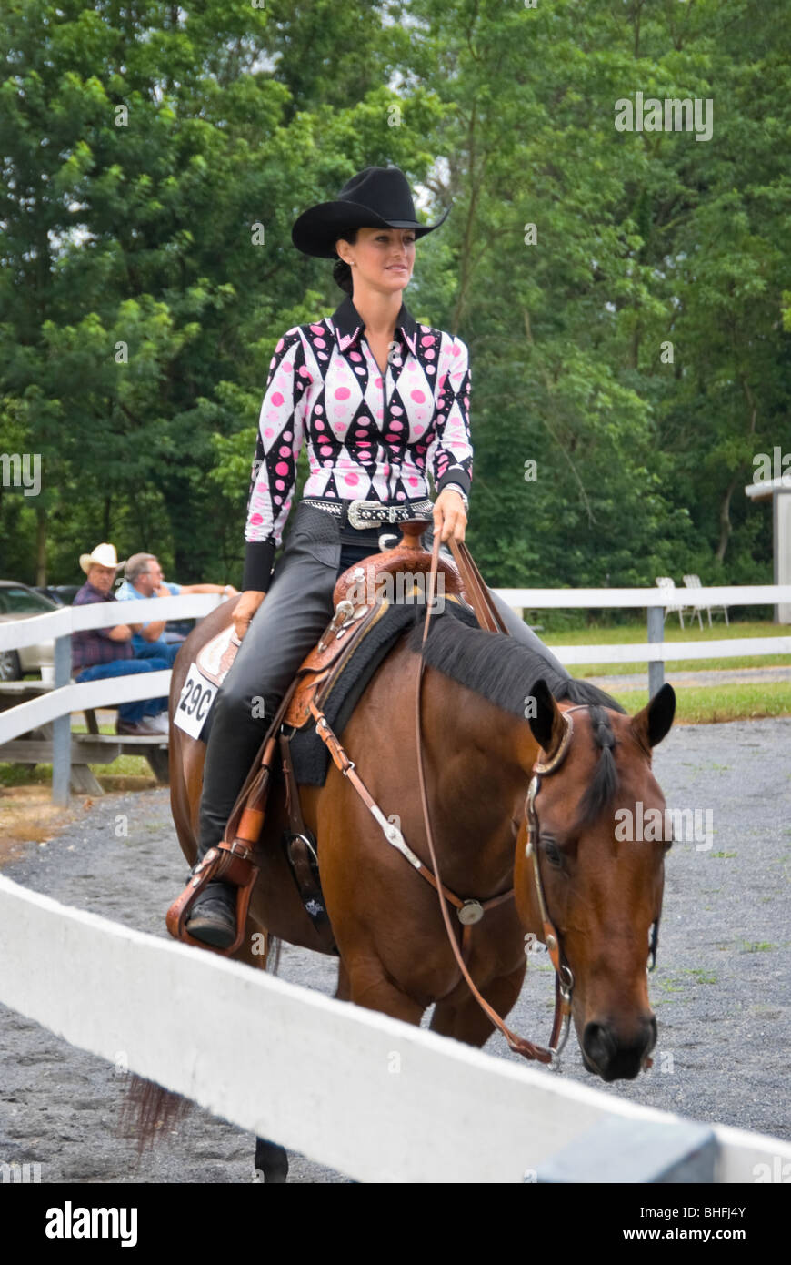Photo de jolie femme équitation plaisir de l'ouest le long de la clôture de fer dans un cheval de concours. Banque D'Images