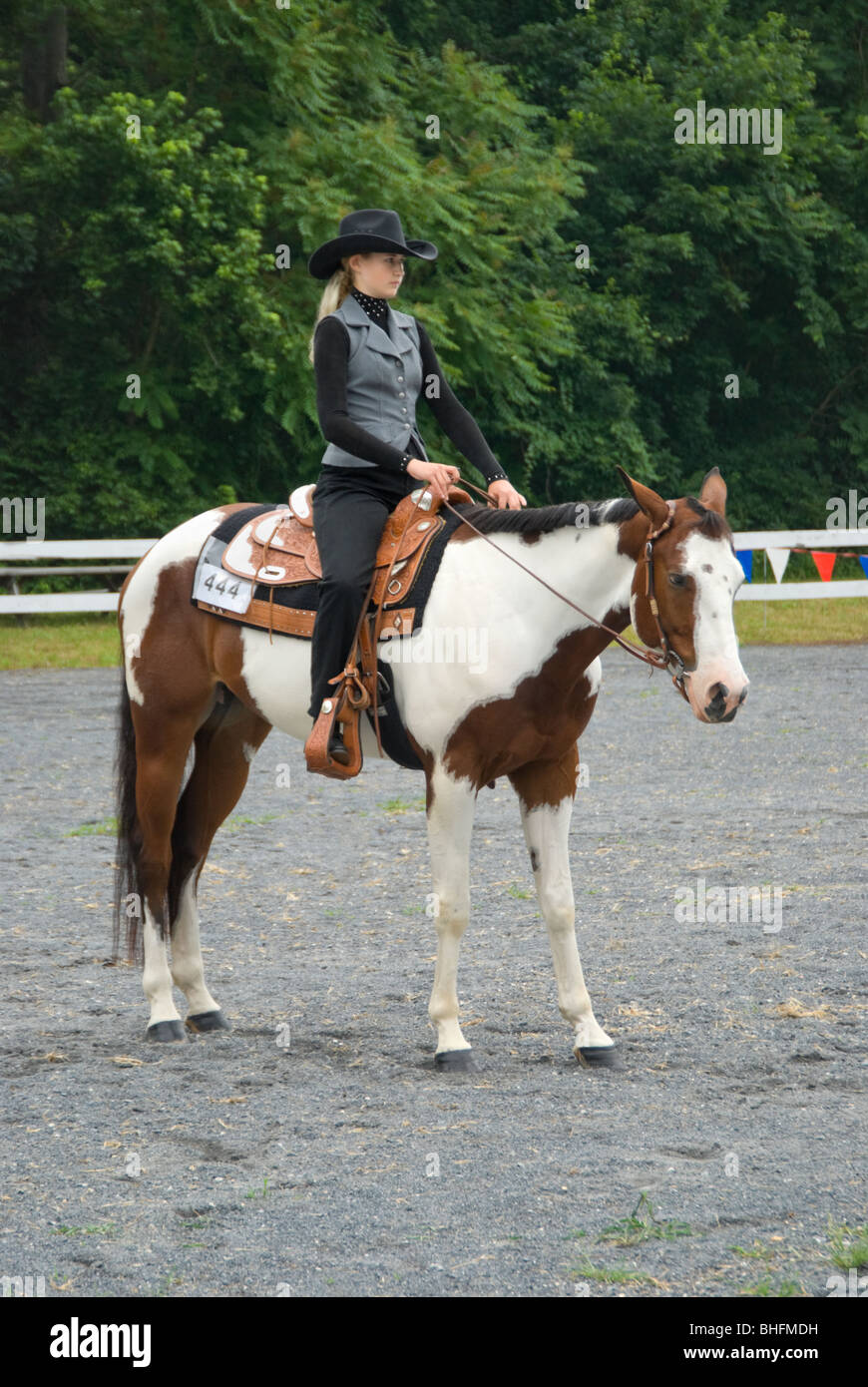 Photo de jeune fille blonde Cheval paint horse tobiano, un de l'ouest dans un plaisir à un rivage concours show. Banque D'Images
