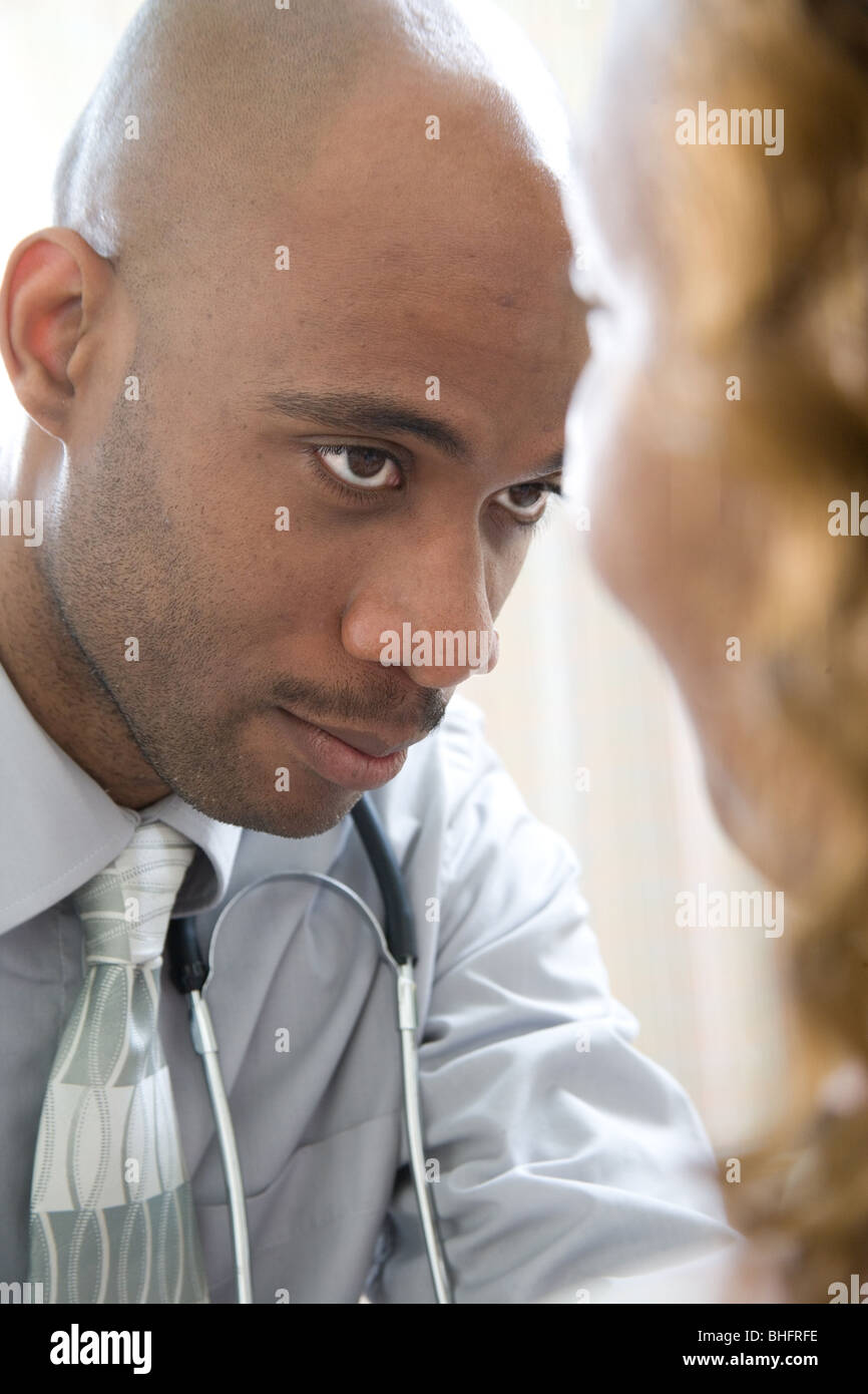 Mâle noir doctor examining patient. Au cours d'un examen physique, un fournisseur de soins de santé studies le corps d'un patient. Banque D'Images