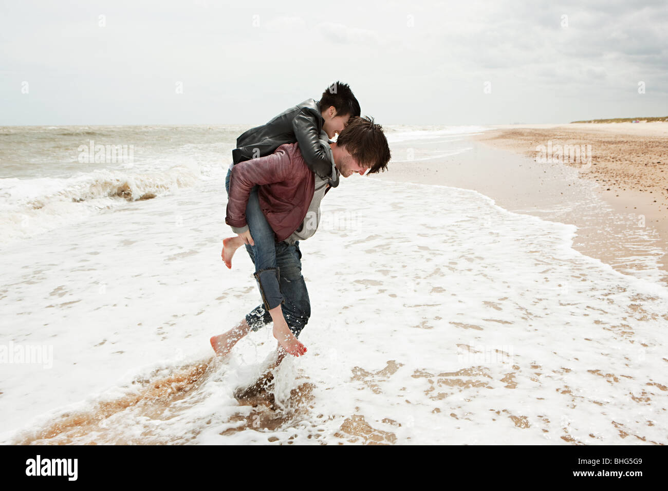 Man giving girlfriend piggyback dans la mer Banque D'Images