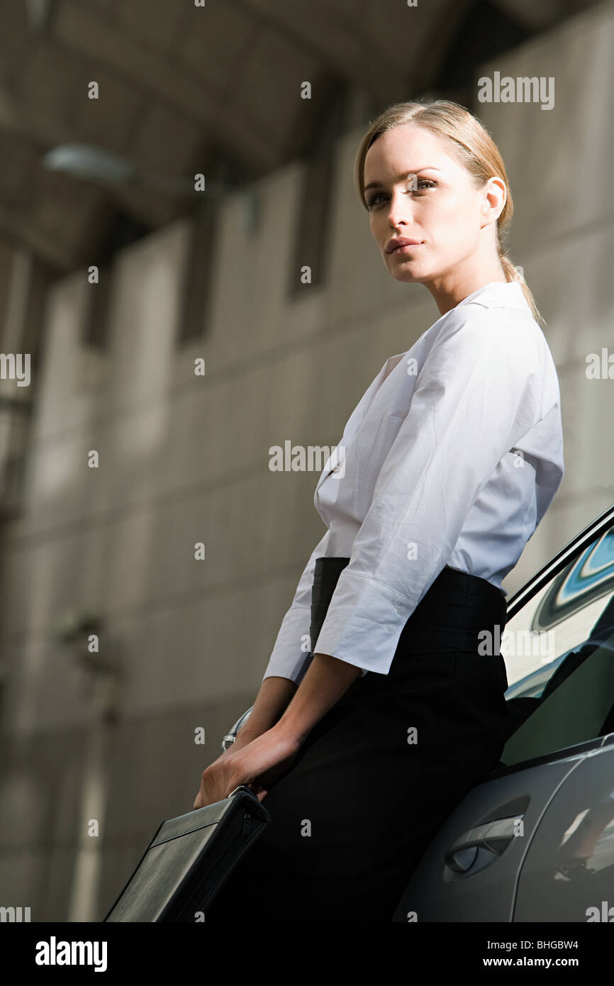 Businesswoman leaning on a car Banque D'Images