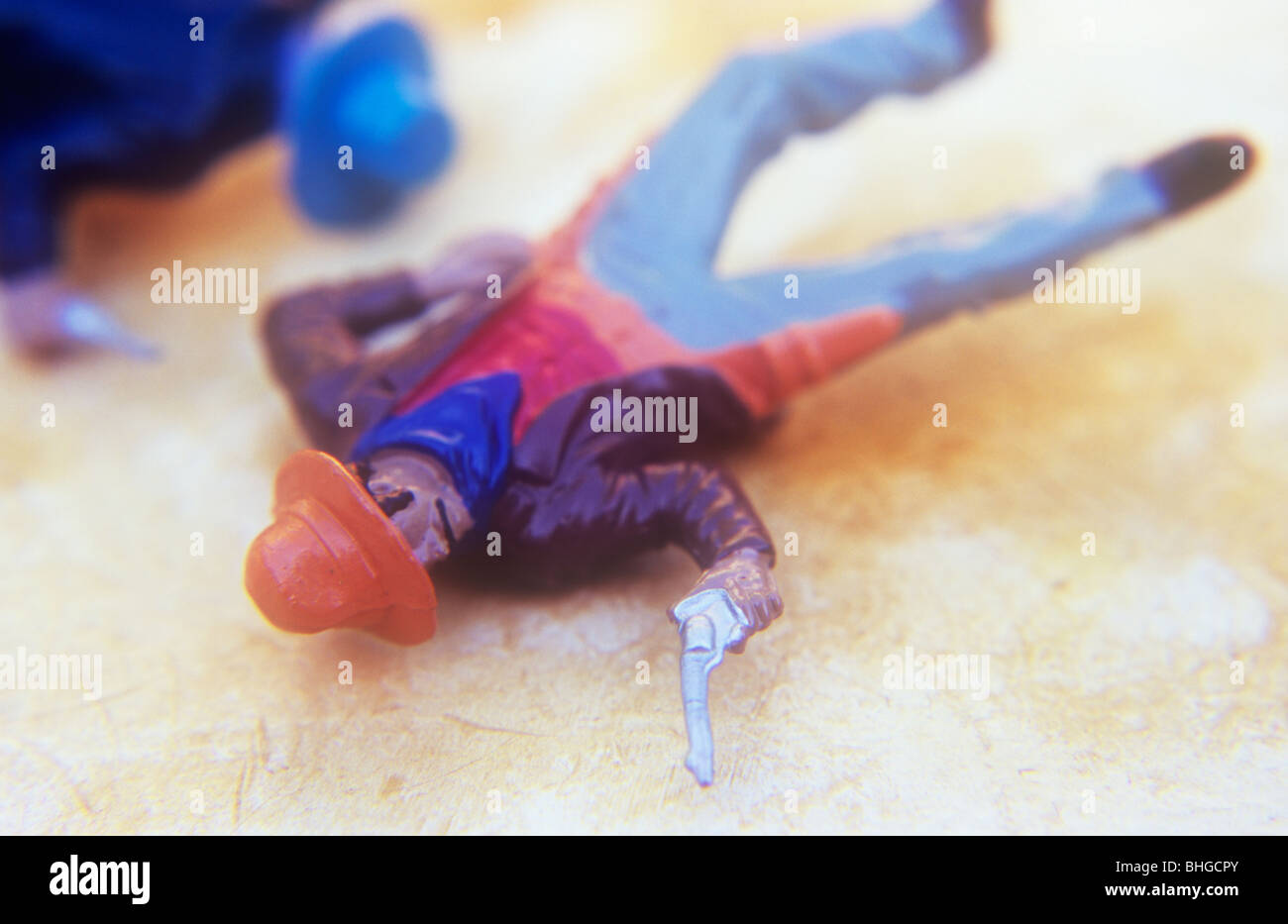 Close up of model of cowboy pointing gun et allongé sur le dos sur fond beige avec une autre se trouvant près de cow-boy par Banque D'Images