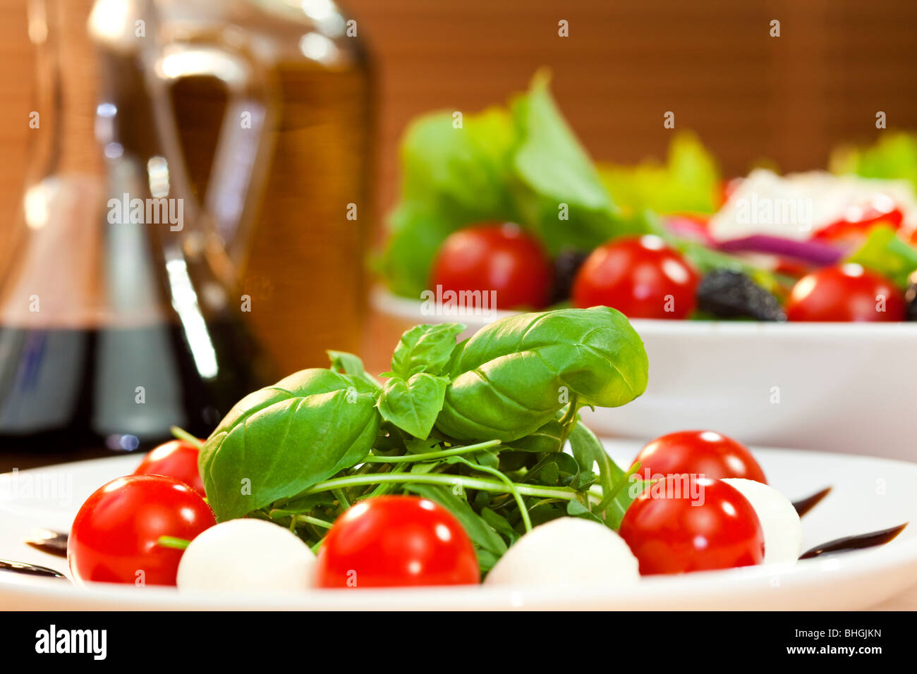 Tomate, mozzarella, salade de roquette à l'huile d'olive et de vinaigre balsamique et basilic vinaigrette garnir tourné en soleil doré Banque D'Images