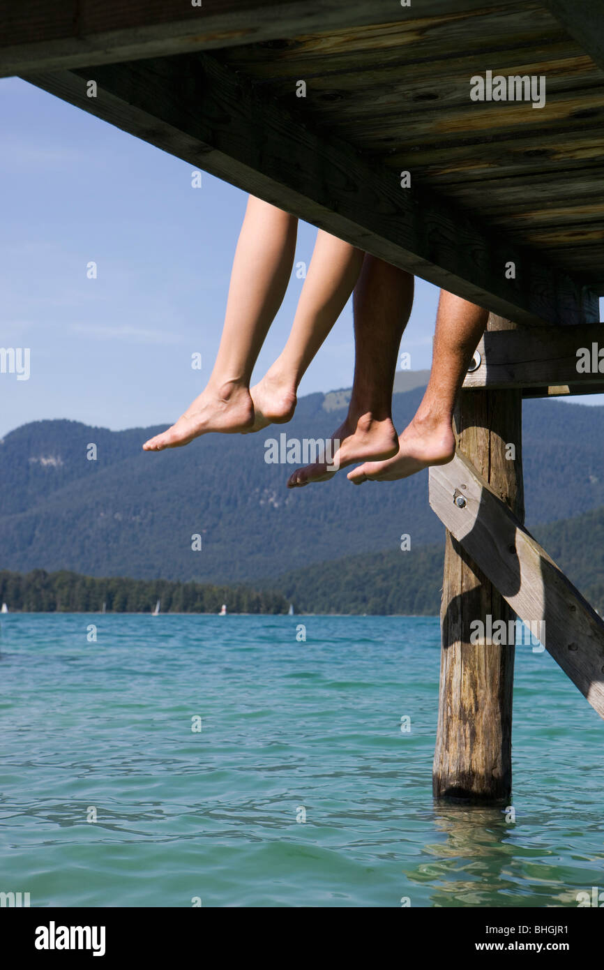 Deux personnes assis pieds nus par un lac Banque D'Images