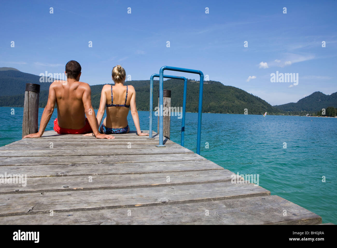 Un couple assis sur un quai près d'un lac Banque D'Images