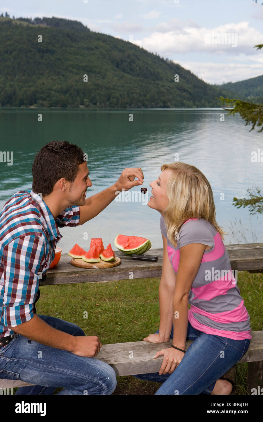 Un jeune couple d'avoir un pique-nique au bord d'un lac Banque D'Images
