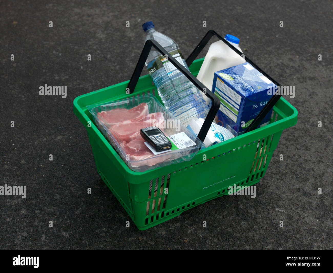 Supermarché Panier contenant du lait, de la viande, un téléphone mobile, le sucre, l'eau en bouteille et d'un plateau Banque D'Images
