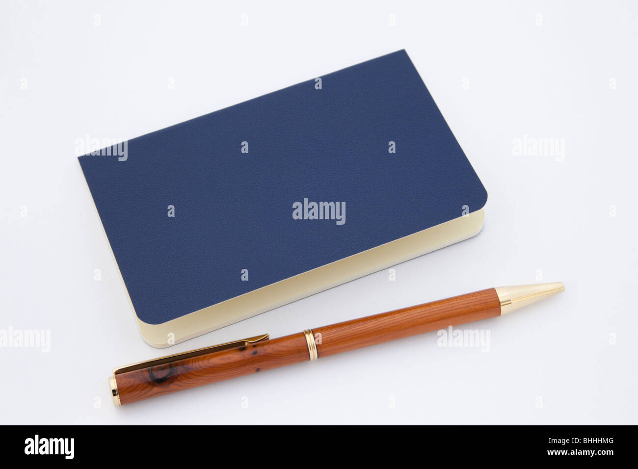 Close-up d'un moleskine bleu portable avec un stylo à bille en bois isolé sur un fond blanc. Banque D'Images