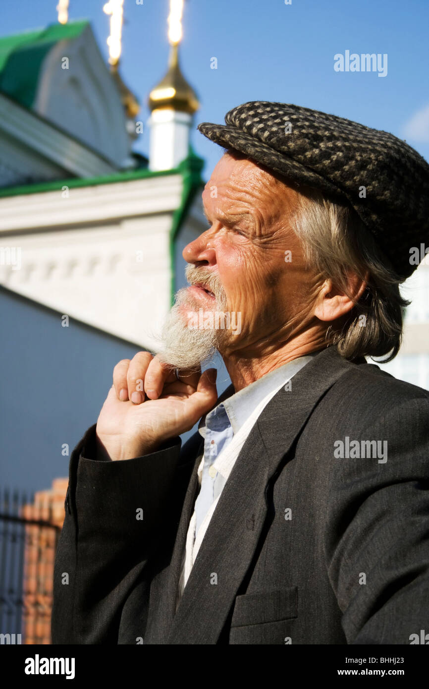 Vieil homme triste contre une cathédrale. Banque D'Images