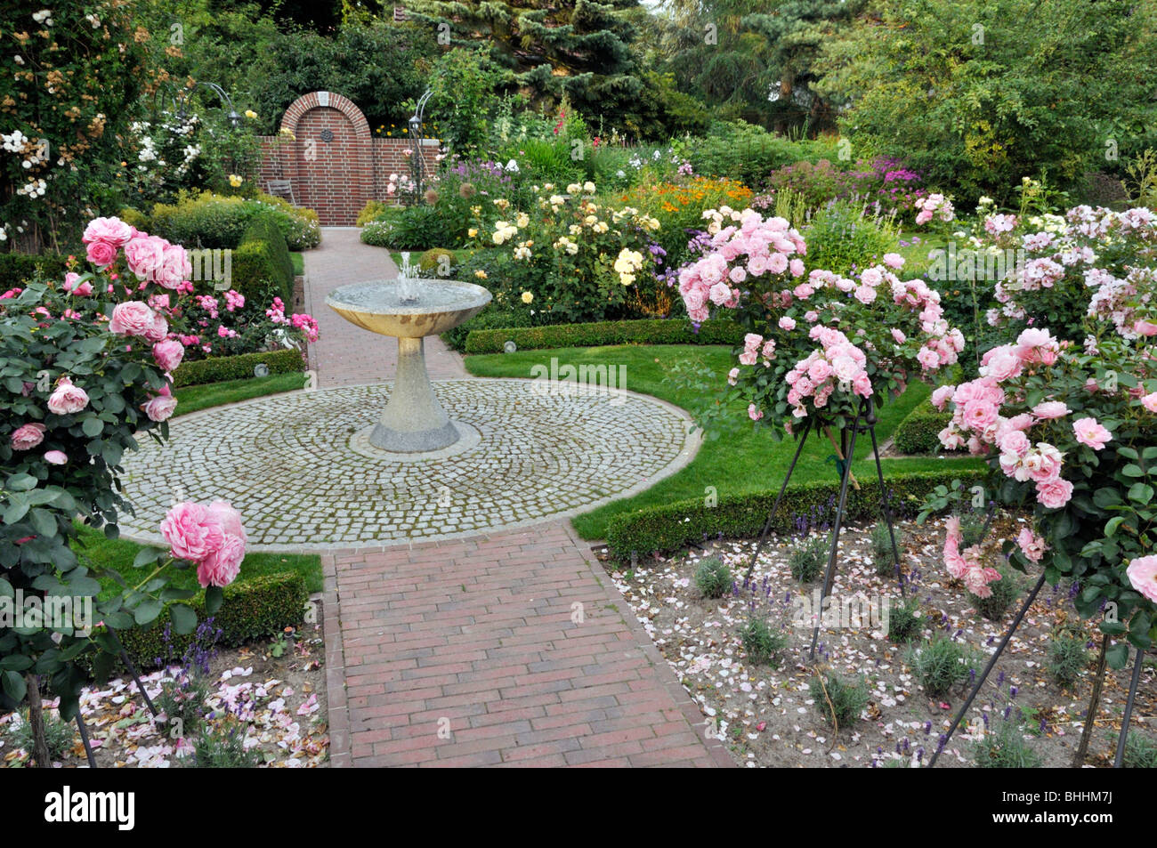 Jardin avec fontaine en granit rose et moitié roses standard Banque D'Images