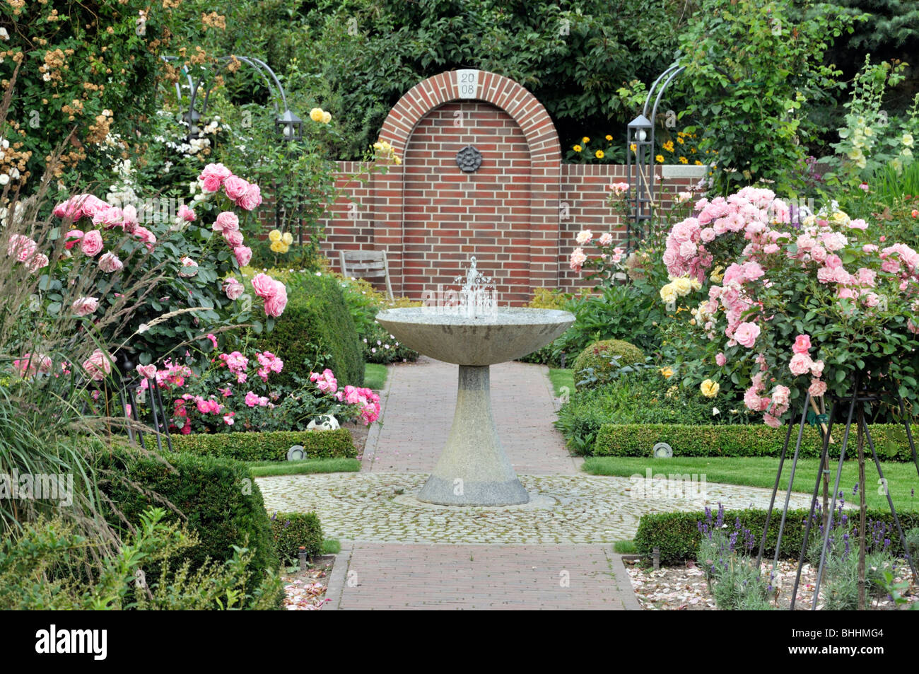 Jardin avec fontaine en granit rose et moitié roses standard Banque D'Images