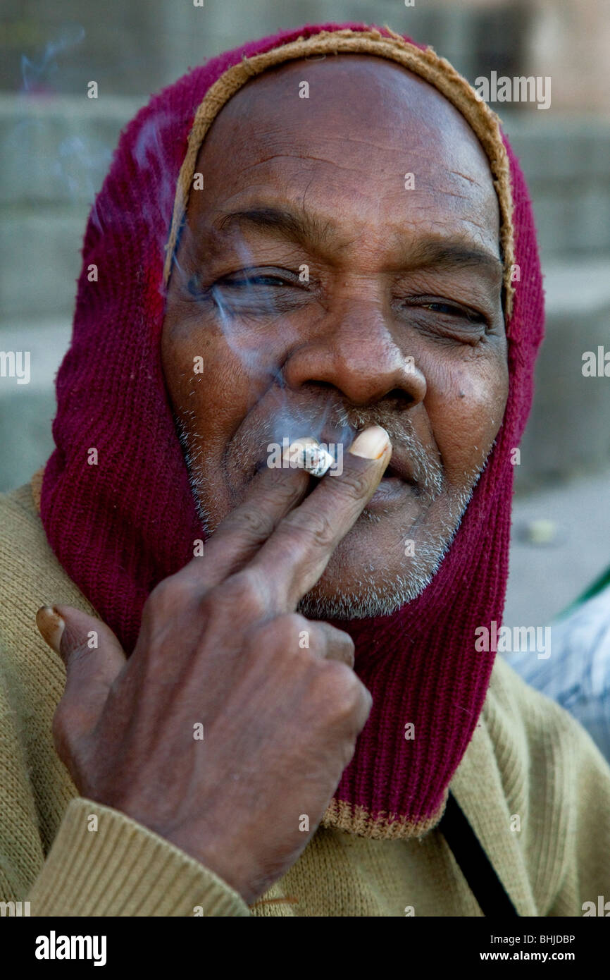 Indien à balaclava cigarette sur les rives du Gange, Varanasi, Inde Banque D'Images
