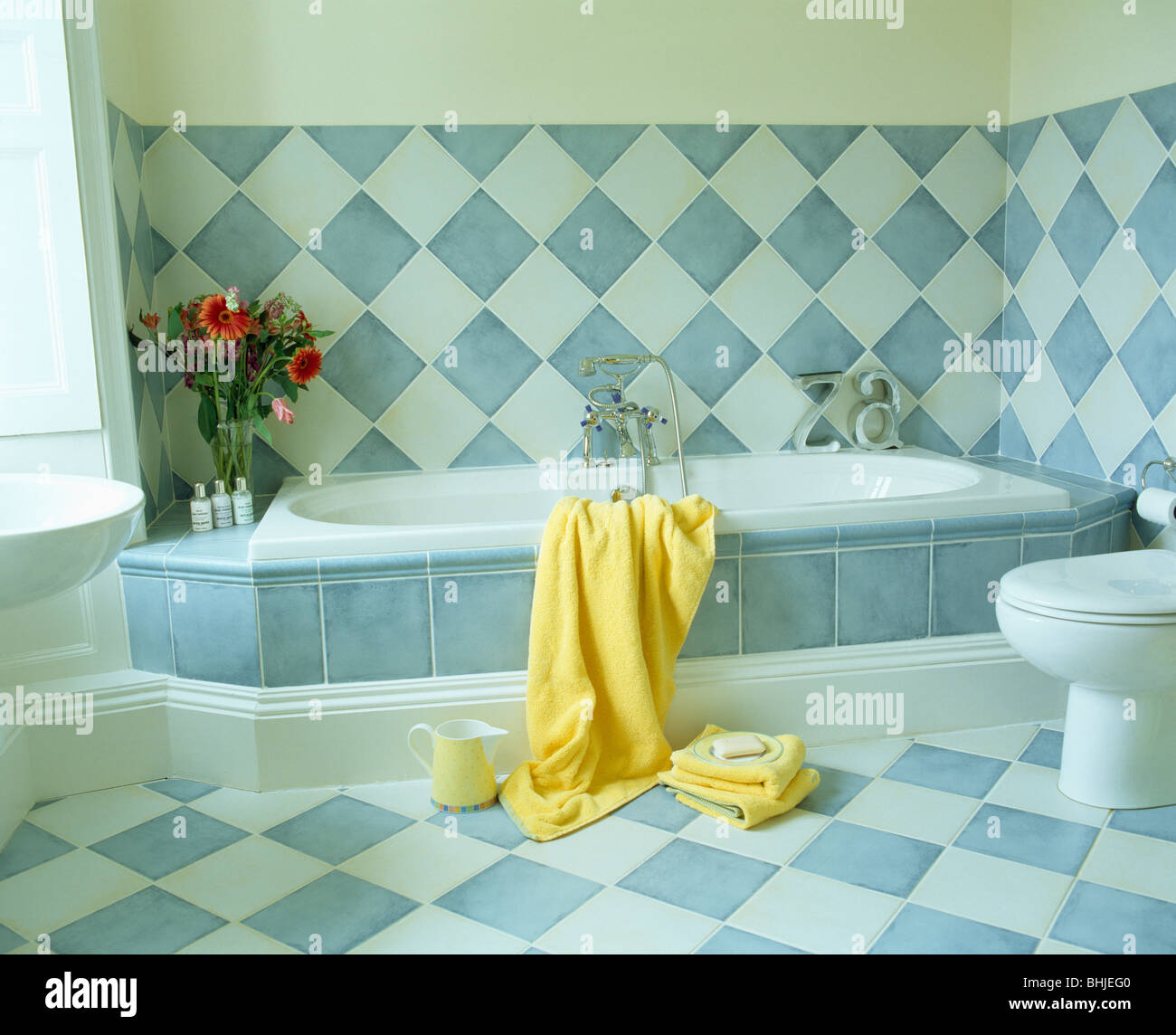 Blanc +bleu à damiers mur carrelé avec baignoire carrelée bleu ci-dessus le Surround dans une salle de bains moderne avec blanc +bleu à damiers marbre Banque D'Images