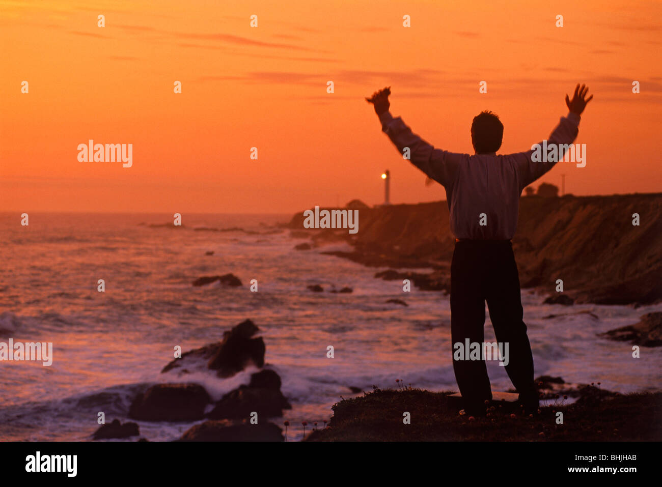 Businessman avec bras levés et de téléphones cellulaires des succès à célébrer la vie et près de Point Arena Phare sur la côte de la californie centrale Banque D'Images