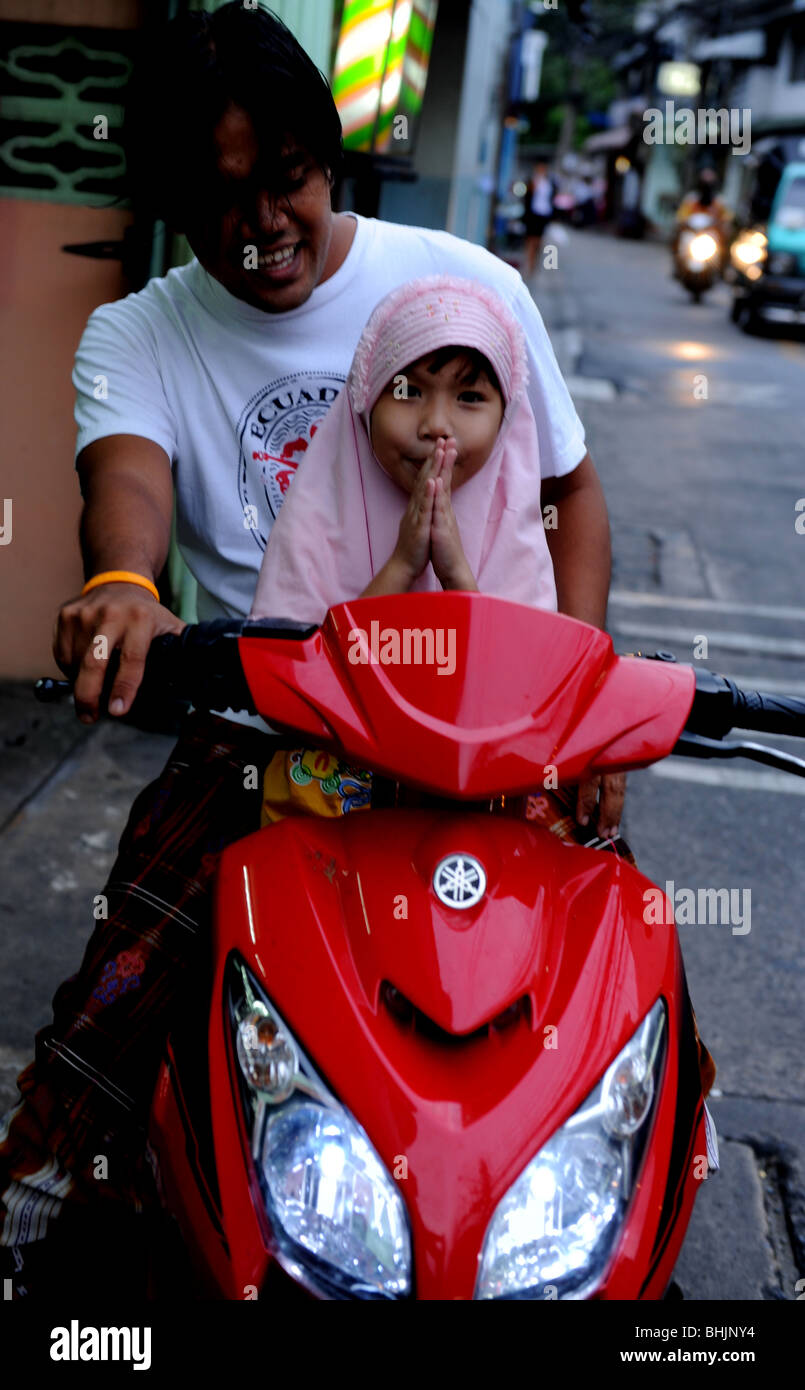 Jeune musulmane avec le père sur moto en vêtements traditionnels en dehors de mosquée wai-ing , bangkok , Thaïlande Banque D'Images