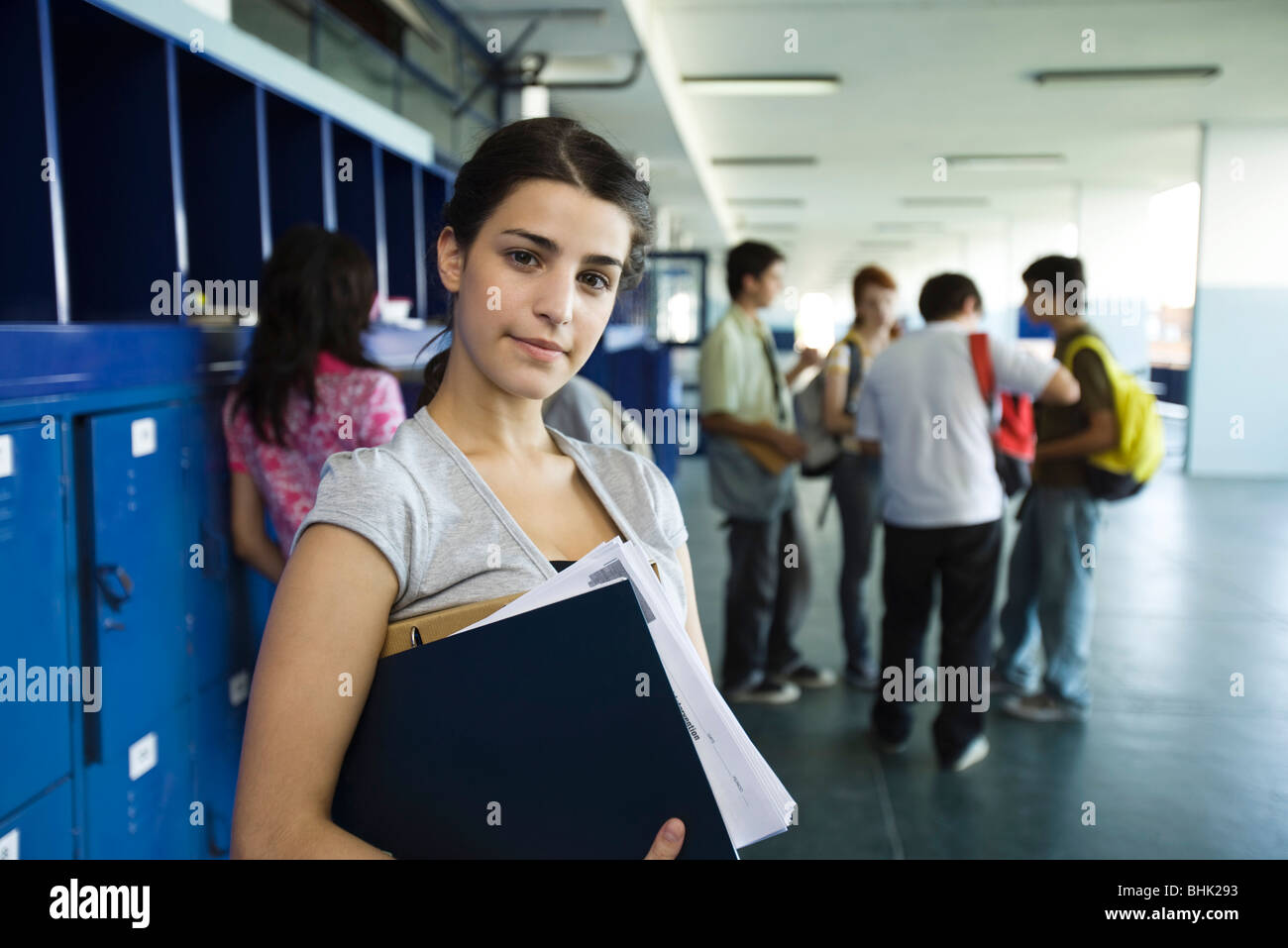 Female high school student standing in hall bordé avec des casiers Banque D'Images