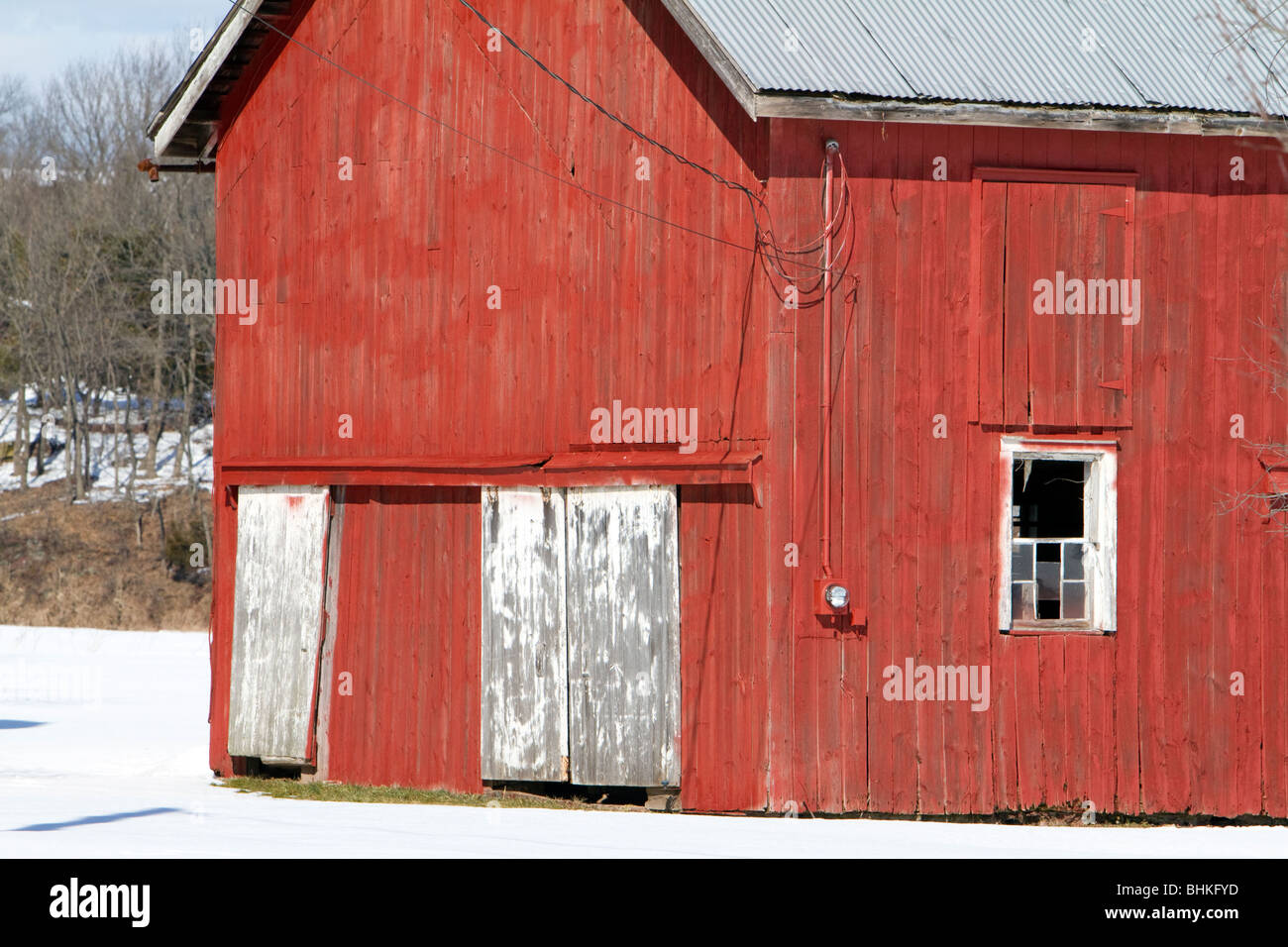 La fin d'une vieille grange rouge. Toit en tôle et peinture décolorée fenêtres brisées. Banque D'Images