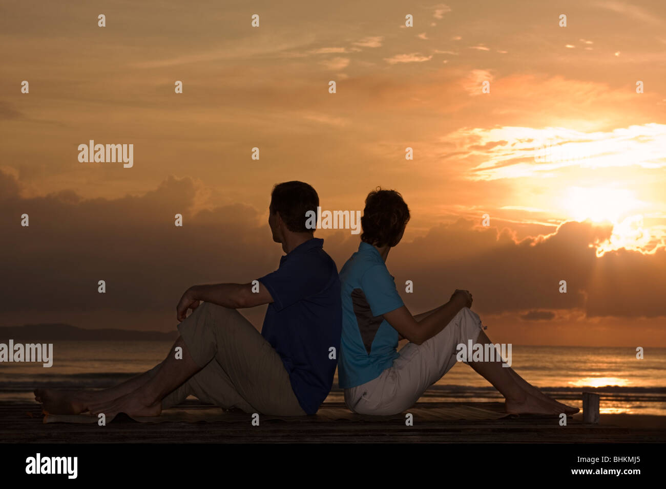 Couple sur une plage en face d'un lever de soleil Banque D'Images