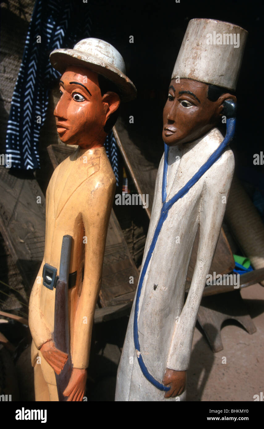 Les sculptures en bois d'un homme blanc avec un casque colonial et de fusil, avec un médecin noir et stéthoscope, dans un marché à Ségou, au Mali. Banque D'Images