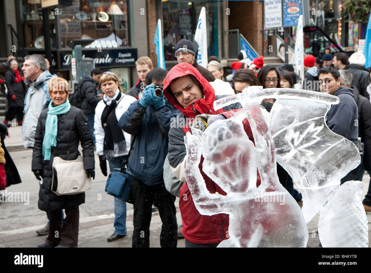 La sculpture sur glace est un artiste travaillant sur sa sculpture de glace alors que la foule dans la rue regarder sur Banque D'Images