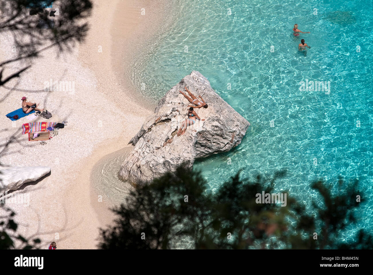 Les gens au soleil dans la plage de Cala Goloritze, Sardaigne, île de l'Italie. Eau bleu clair dans la baie de Cala Goloritzè, Mer Méditerranée Banque D'Images