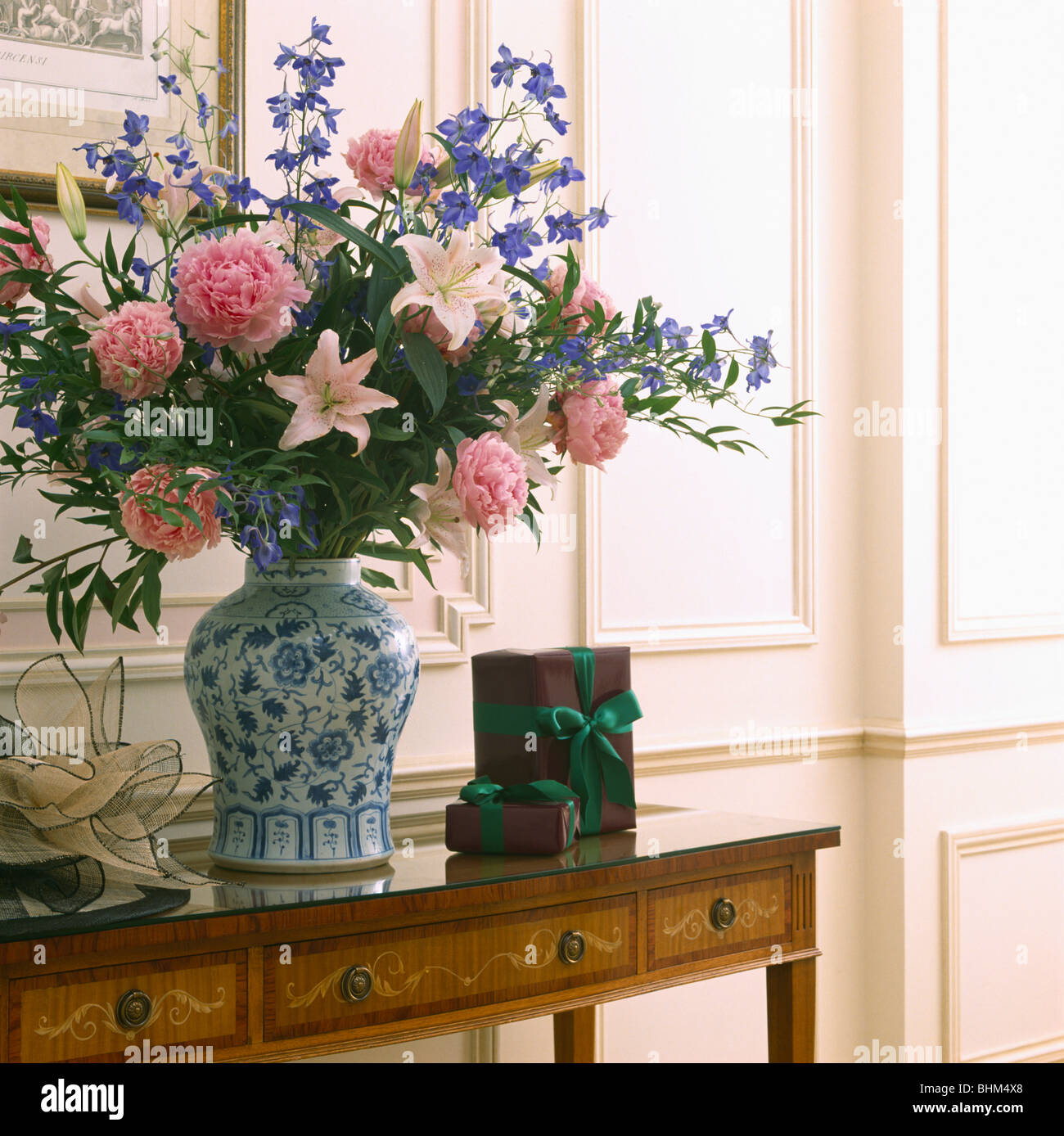 Close-up of flower arrangement informel de rose et bleu de fleurs dans vase blanc +bleu sur table console antique Banque D'Images