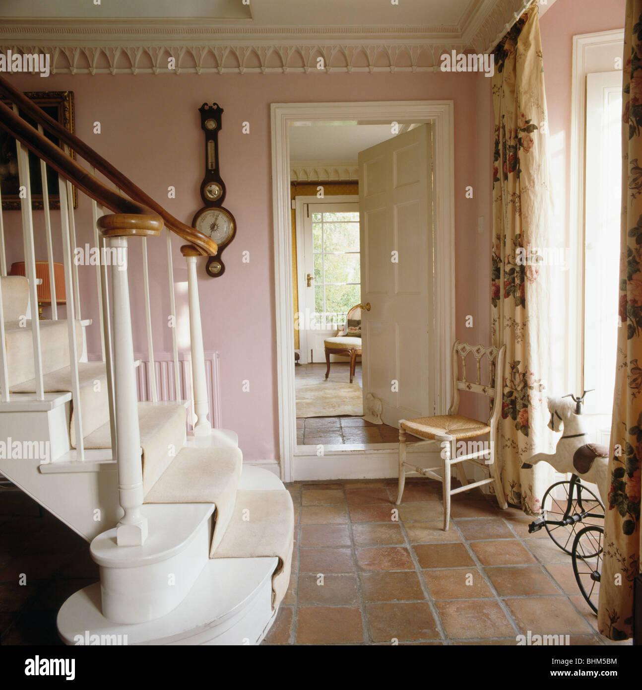 Carreaux de sol en pierre et une chaise à côté d'ouvrir la porte de salle à manger en pays rose hall avec escalier blanc et corniche Gothique Banque D'Images