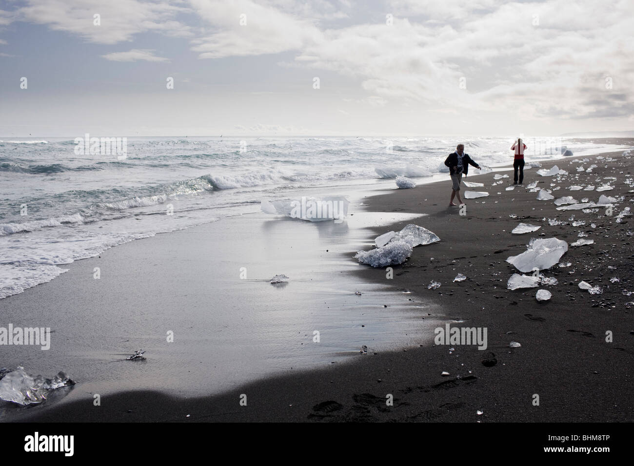 Les touristes à pied à la plage ci-dessous, l'Islande Jokulsarlon Banque D'Images