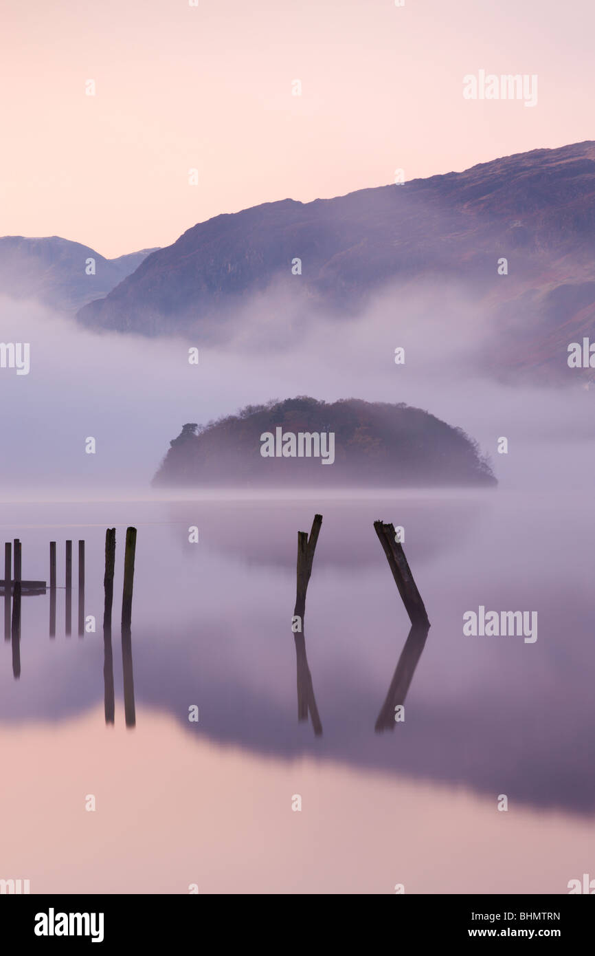 Poteaux de bois et St Herbert's Island sur Derwent Water à l'aube d'un matin brumeux, Parc National de Lake District, Cumbria, Angleterre Banque D'Images Poteaux de bois et St Herbert's Island sur Derwent Water à l'aube d'un matin brumeux, Parc National de Lake District, Cumbria, Angleterre Banque D'Images