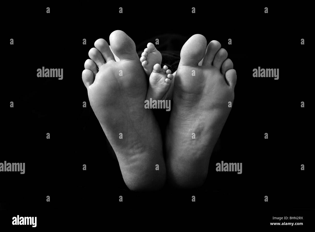 Les pieds d'un nouveau-né placé à côté de son père pour un comparatif de  taille en noir et blanc Photo Stock - Alamy