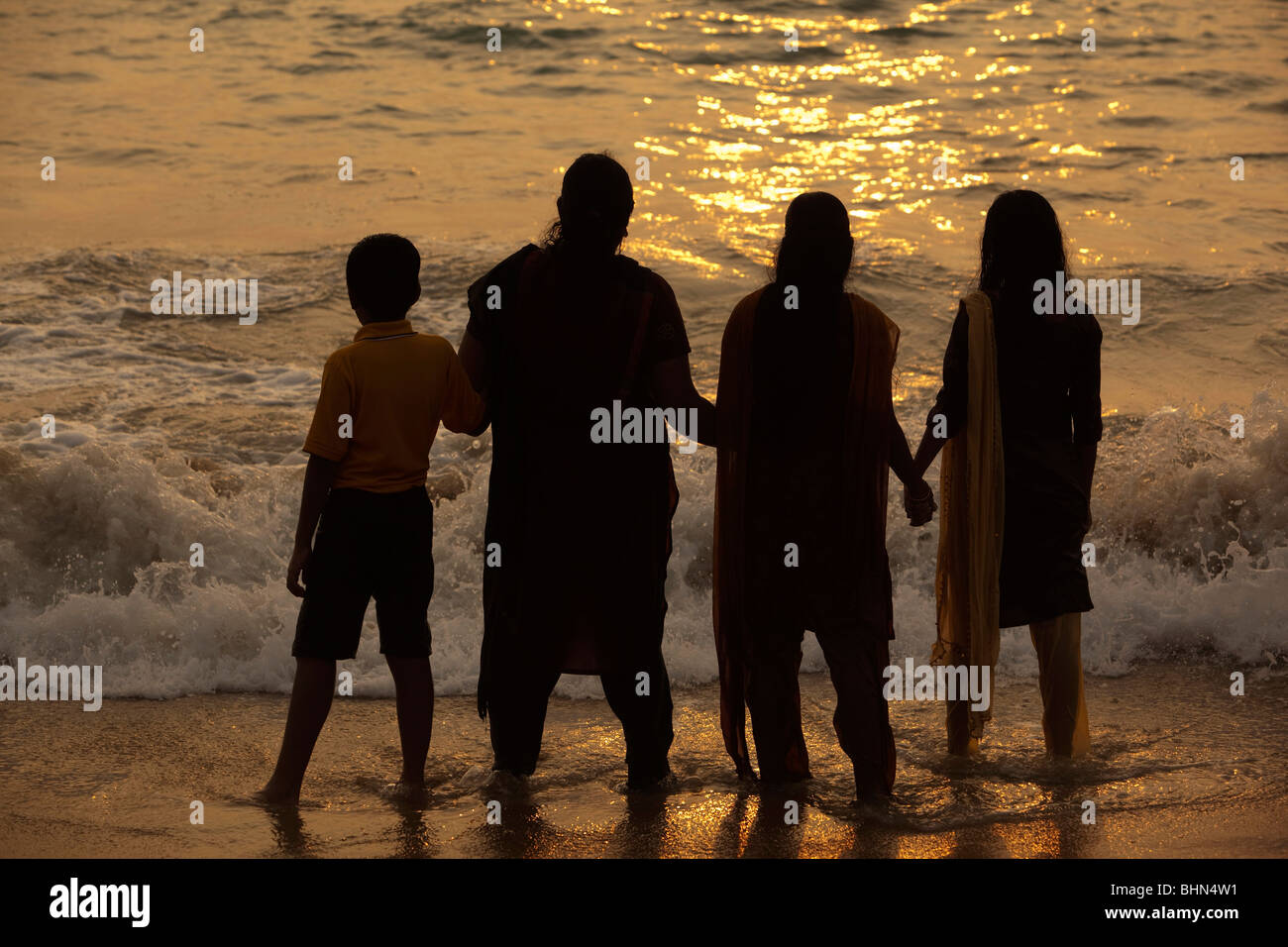 L'Inde, le Kerala, Kovalam, Hawah Beach (Eve), Indian family de la mer au coucher du soleil Banque D'Images