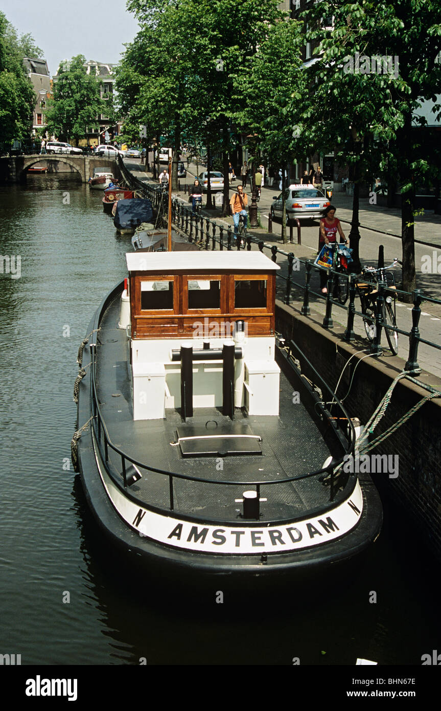 Péniche hollandaise amarrés sur un canal à côté d'une rue bordée d'arbres, Amsterdam, Pays-Bas Banque D'Images