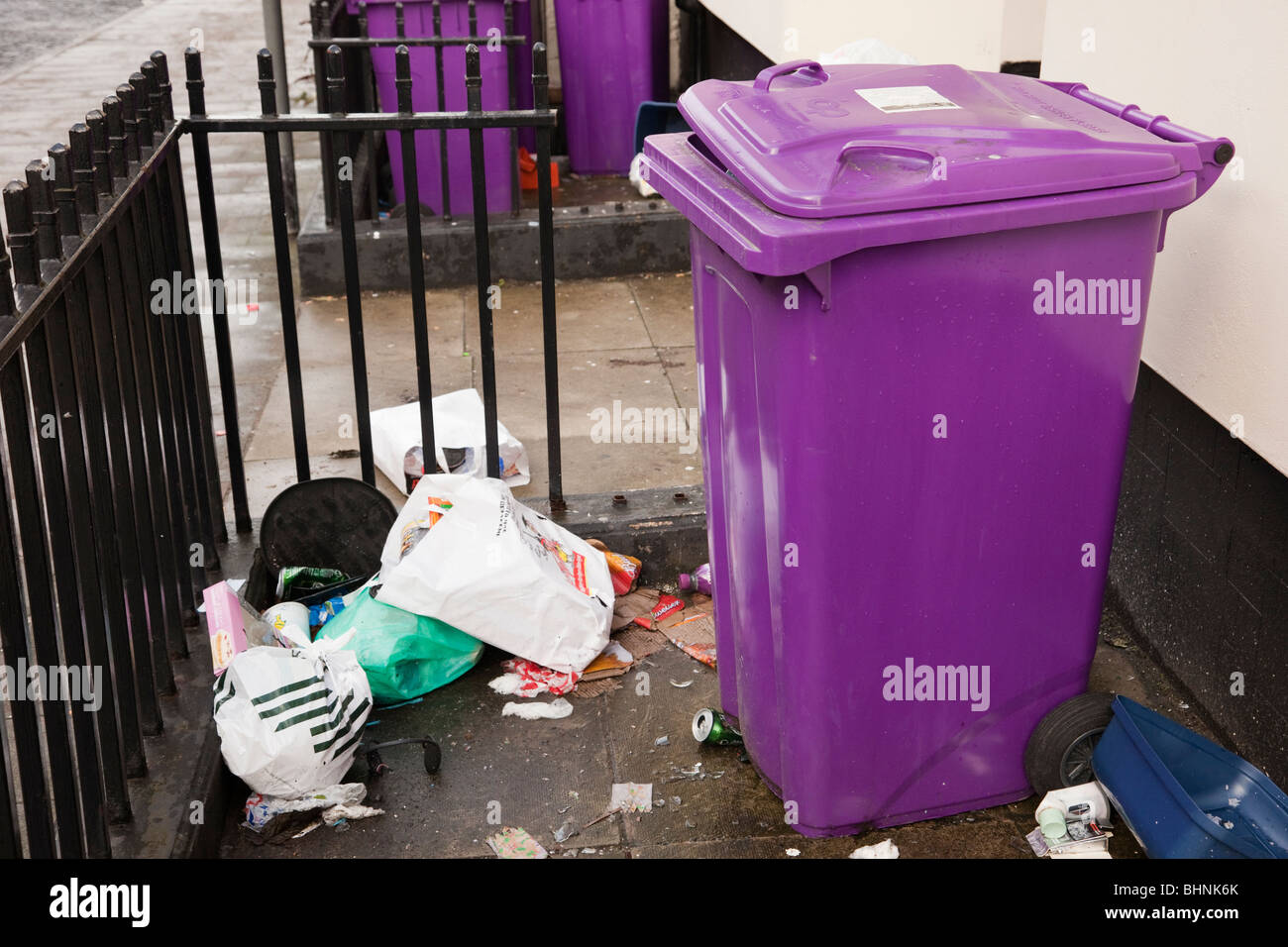 En Angleterre, Royaume-Uni, Grande Bretagne. Représentant une poubelle  violette et d'ordures dans des sacs en plastique dans la cour avant on  urban street Photo Stock - Alamy