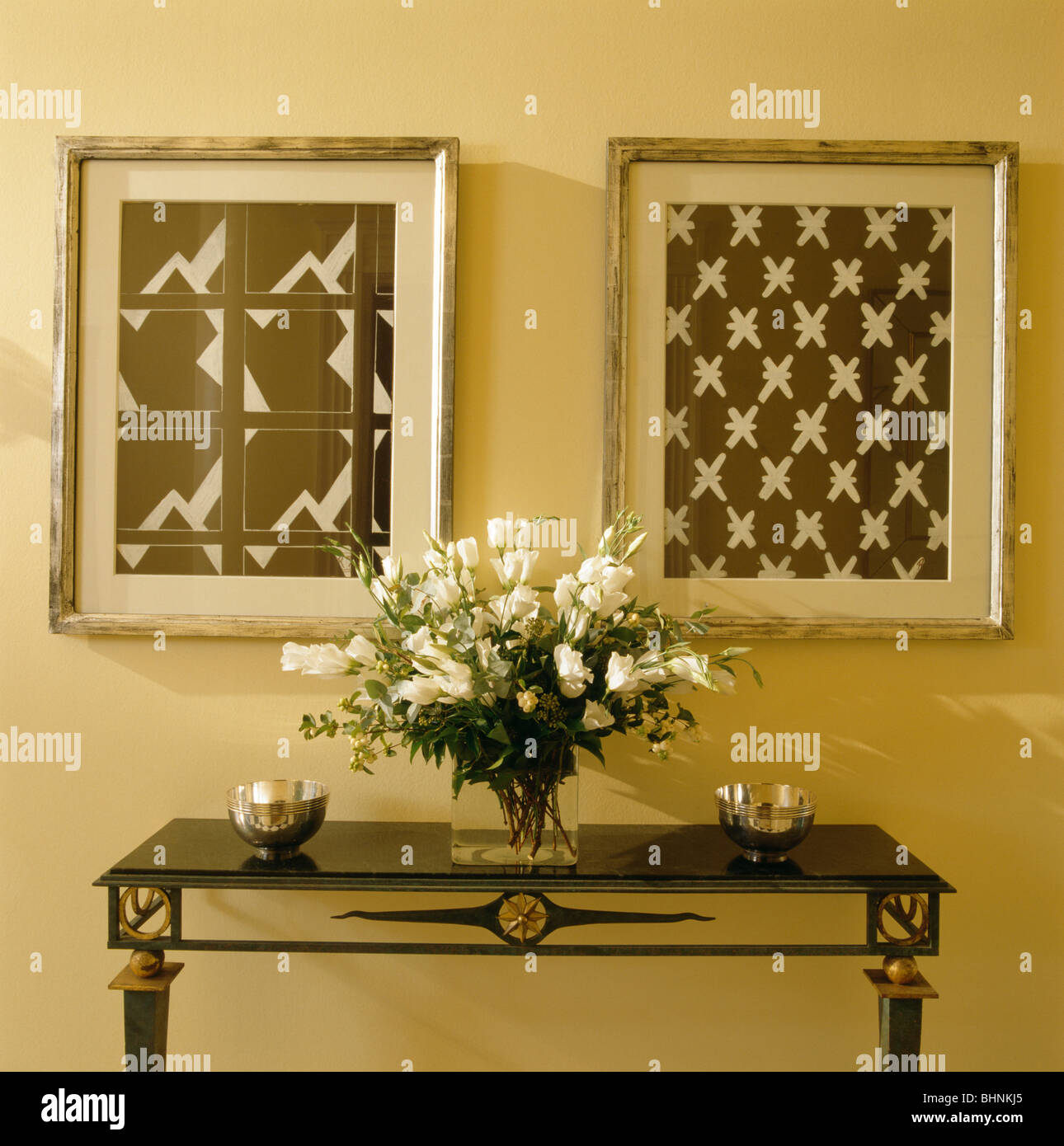 Black +white abstract photos encadrées fleurs blanches en vase en verre sur table console hall à la crème Banque D'Images