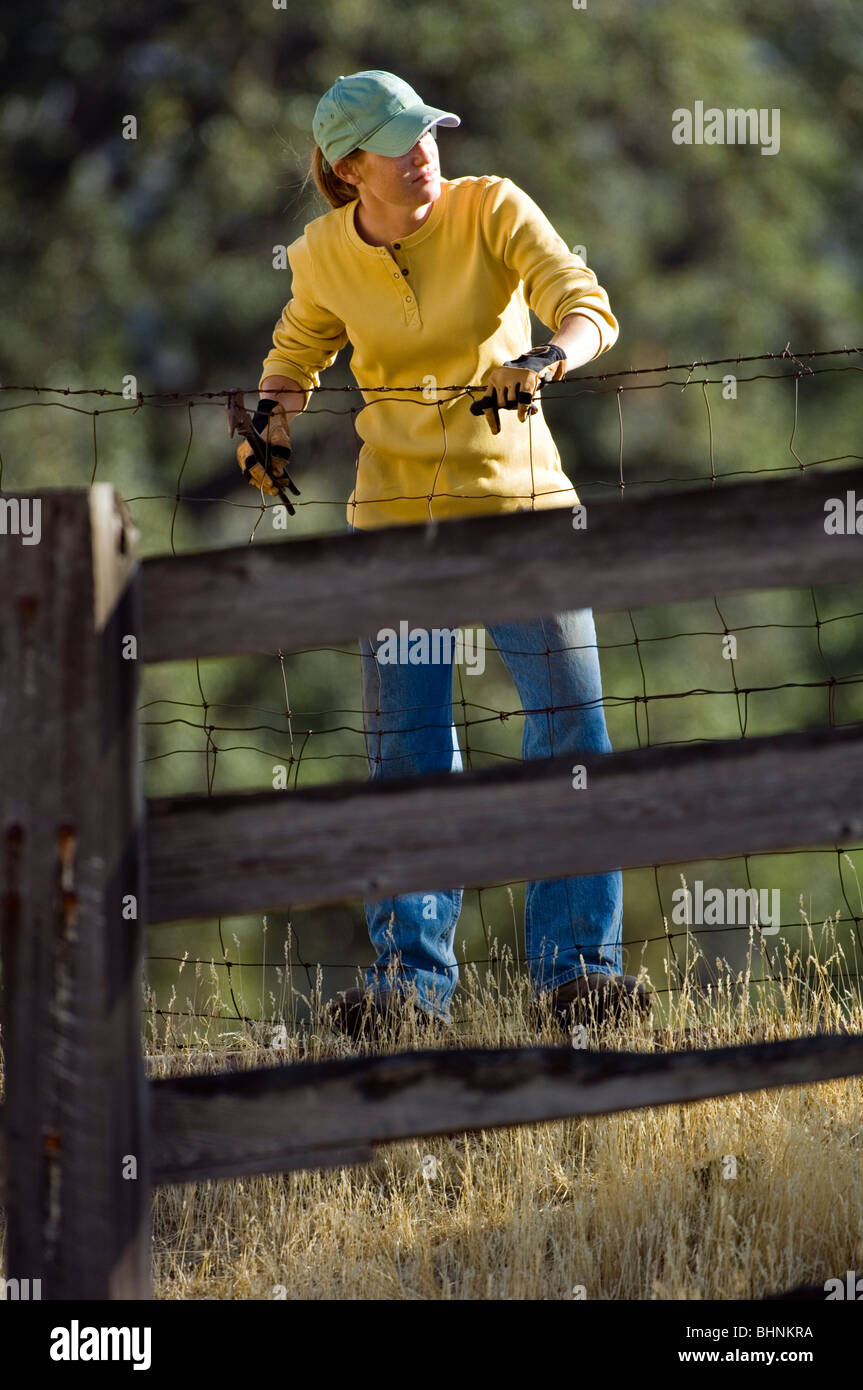 Ranch Hand féminin réparer une clôture sur un ranch Banque D'Images