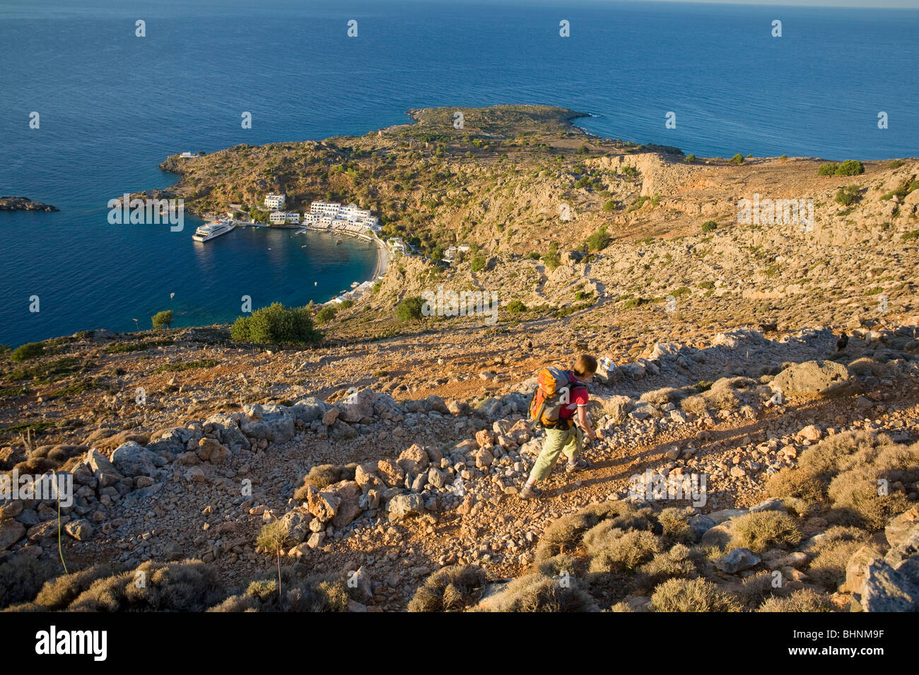 Randonneur sur un sentier au-dessus de Loutro village, Montagnes Blanches, Crète, Grèce. Banque D'Images