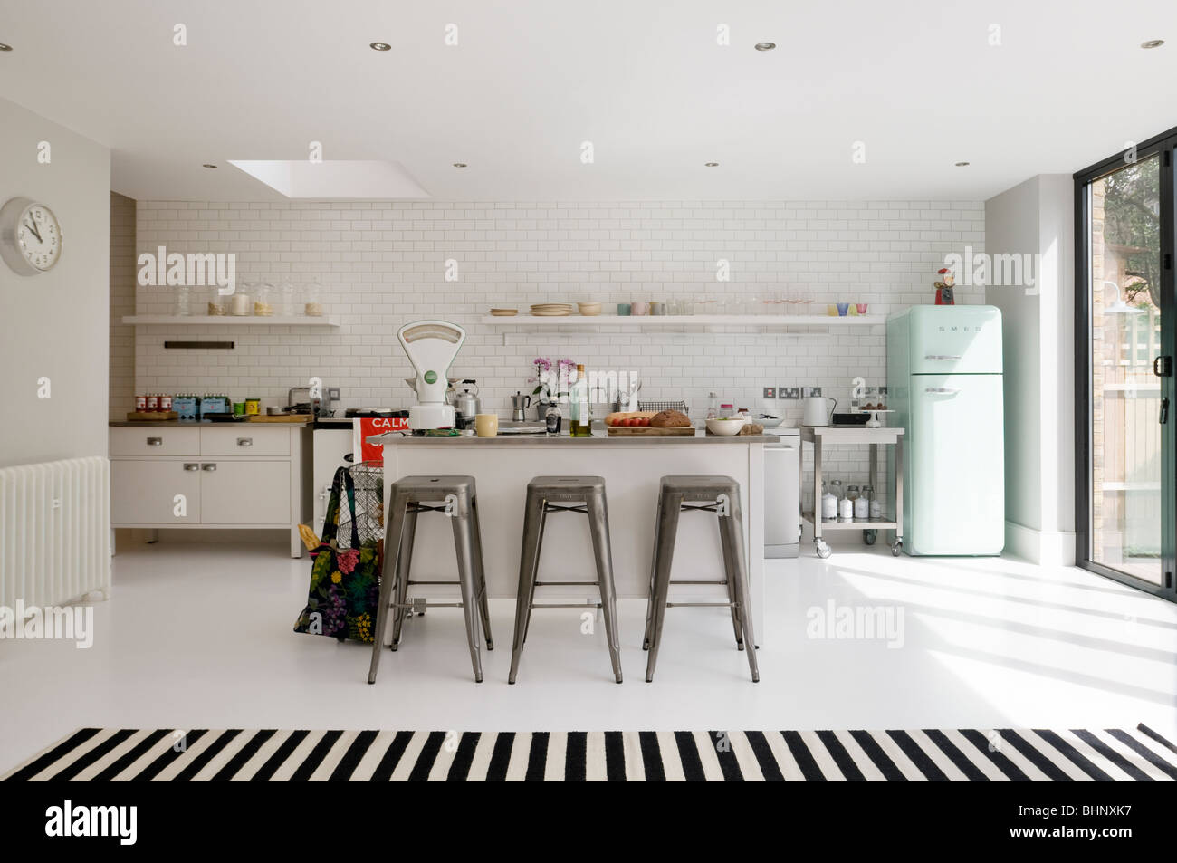Plan ouvert cuisine carrelée de blanc avec tabourets et un réfrigérateur rétro Banque D'Images