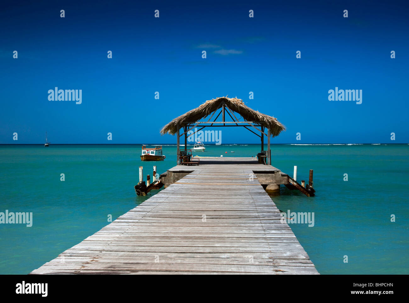 Le toit de chaume jetée à Pigeon Point Heritage Park Tobago contre un ciel bleu et l'aigue-marine mer. Banque D'Images